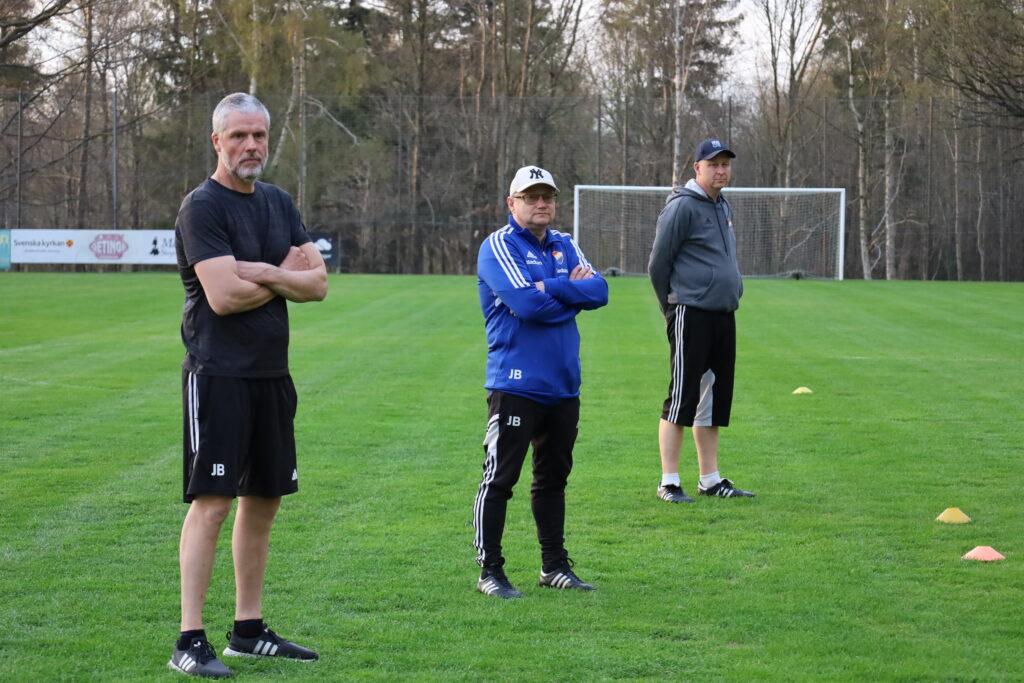 Jörgen Bengtsson, Jan Bengtsson och Ola Larsson står på fotbollsplan och kollar på spelarna.