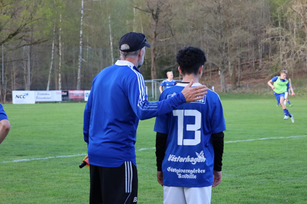 Tränare klappar fotbollsspelare på ryggen.