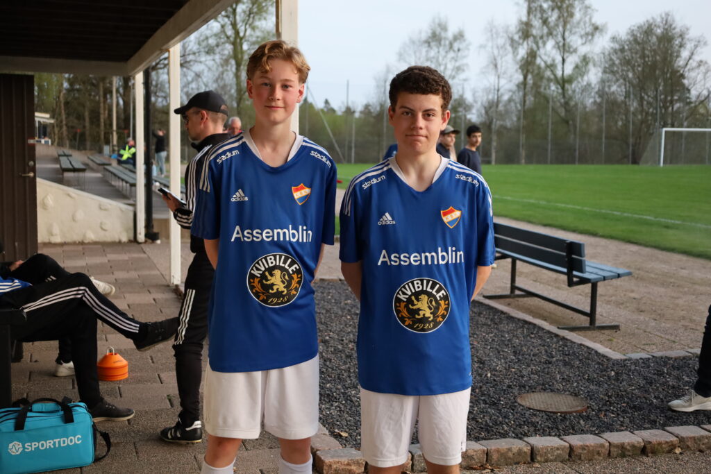 Anton Larsson och Isak Bengtsson ler framför kameran. De har deras blå matchställ på sig och har händerna bakom ryggen.